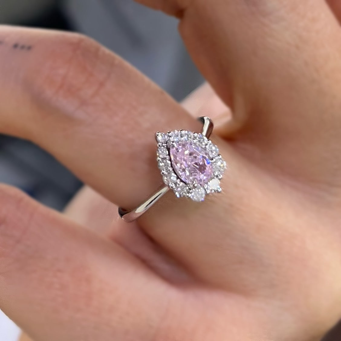 Диамантен пръстен със сапфир в розов цвят, поставени върху тънка златна халка от бяло злато.